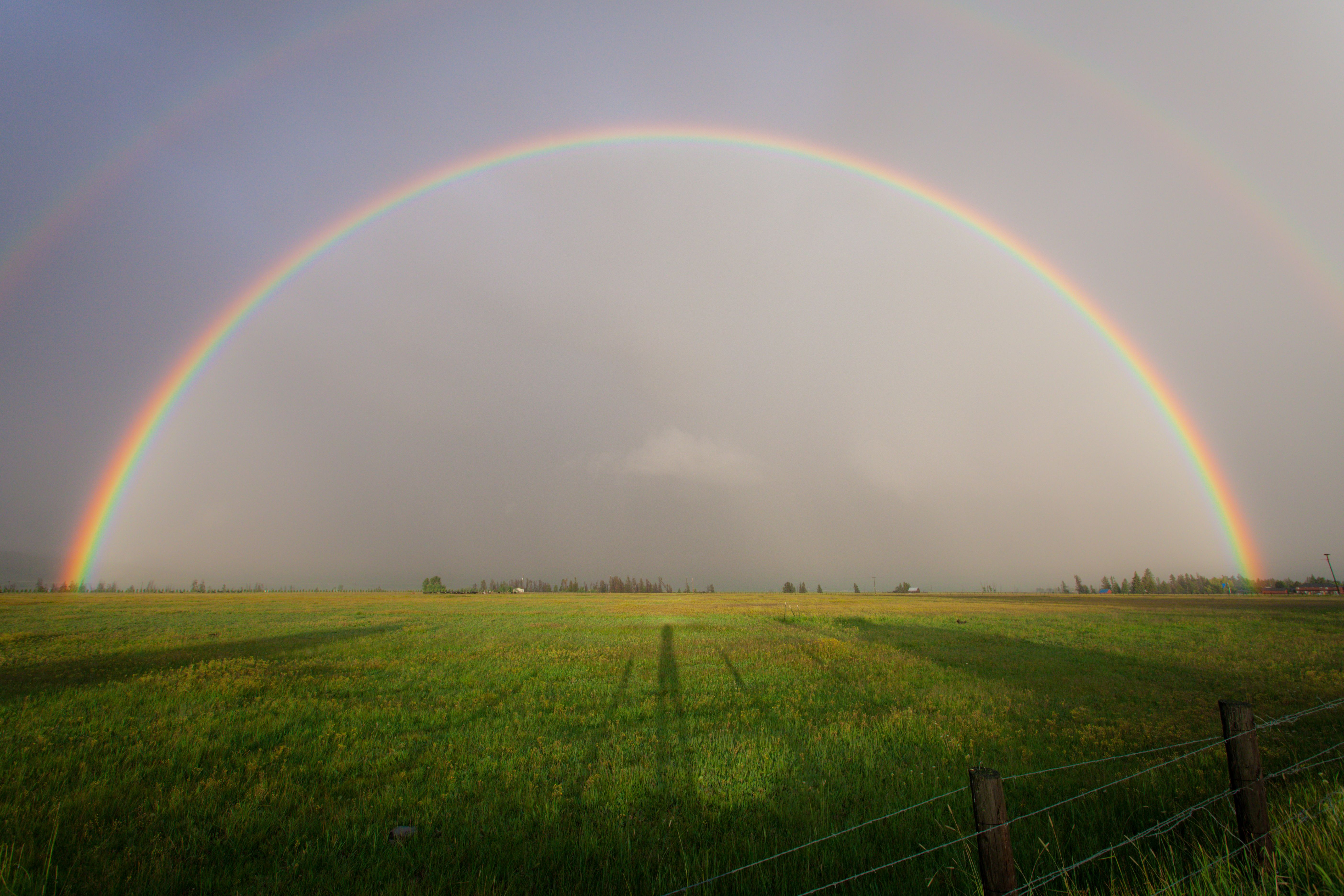 Full rainbow arching over a green farmland countryside